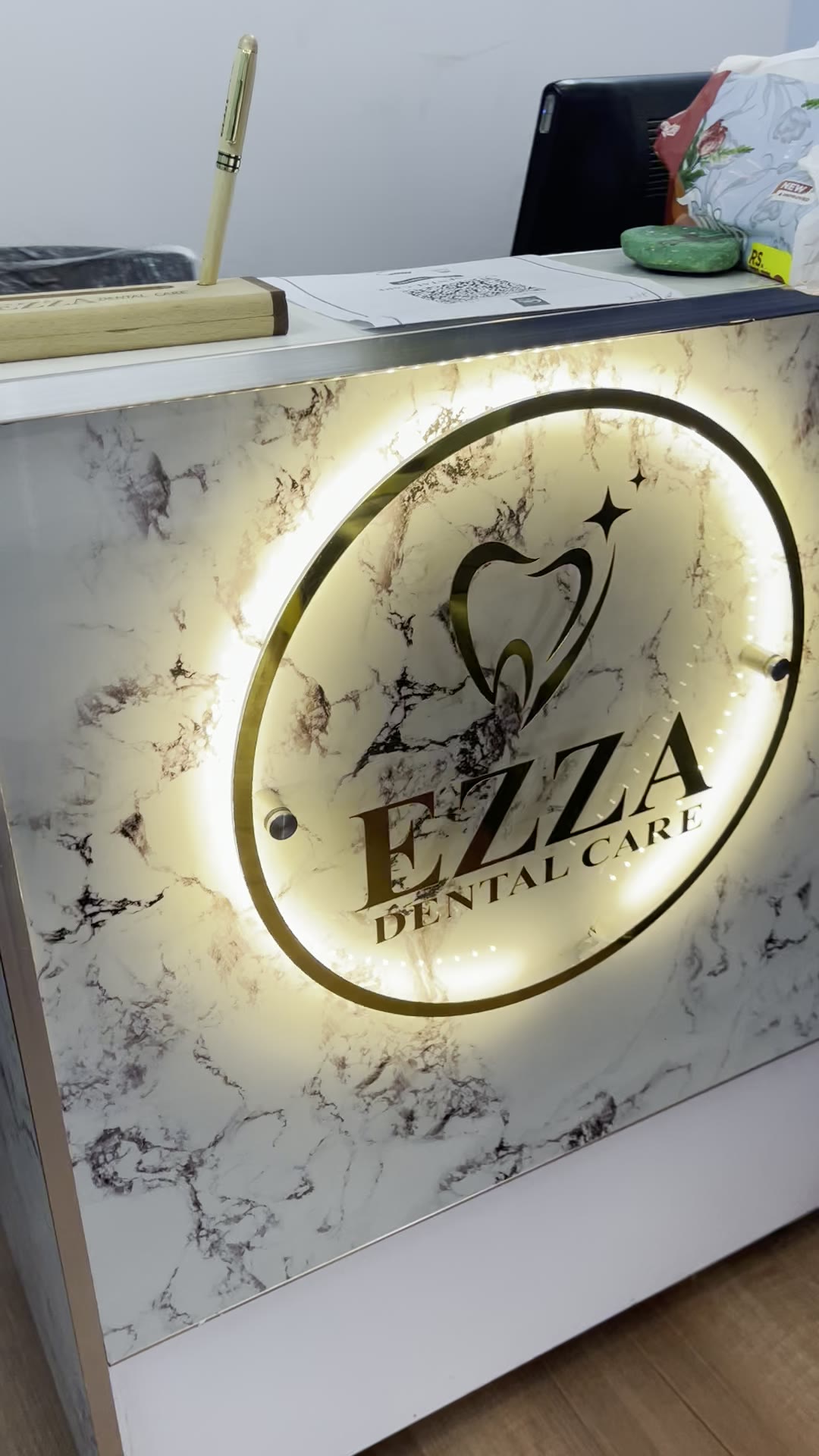 Illuminated Ezza Dental Care logo at reception